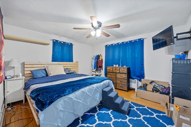 bedroom featuring hardwood / wood-style flooring, radiator heating unit, and ceiling fan