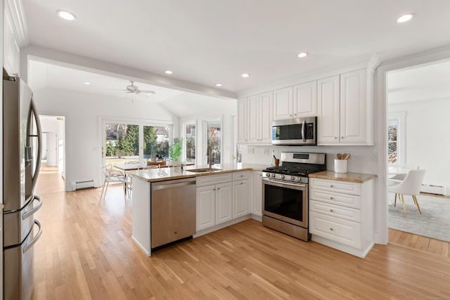 kitchen with stainless steel appliances, white cabinets, light wood-type flooring, and kitchen peninsula