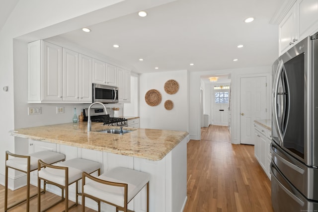 kitchen featuring light stone counters, appliances with stainless steel finishes, kitchen peninsula, and white cabinets