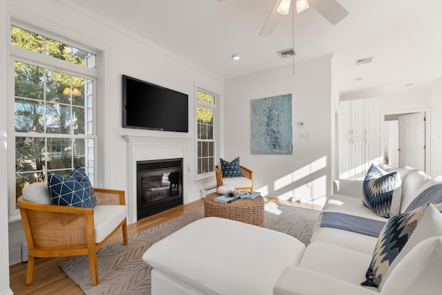 living room featuring ornamental molding, light hardwood / wood-style floors, and ceiling fan