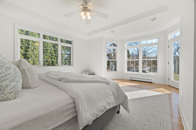 bedroom with ceiling fan, a baseboard radiator, multiple windows, and hardwood / wood-style flooring