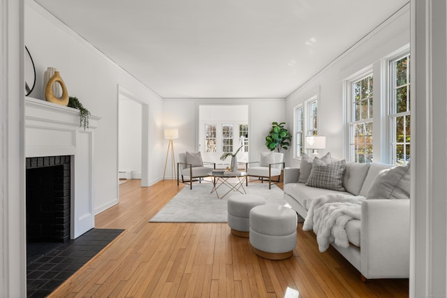 living room with wood-type flooring, a brick fireplace, plenty of natural light, and crown molding