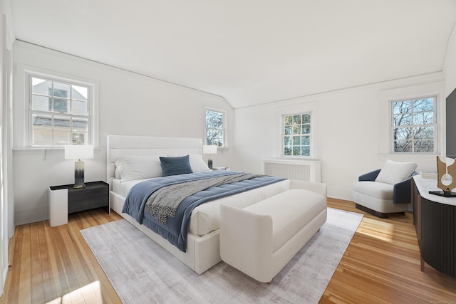 bedroom featuring wood-type flooring, lofted ceiling, and radiator heating unit