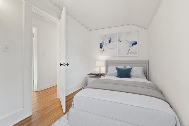 bedroom with hardwood / wood-style flooring, crown molding, and vaulted ceiling