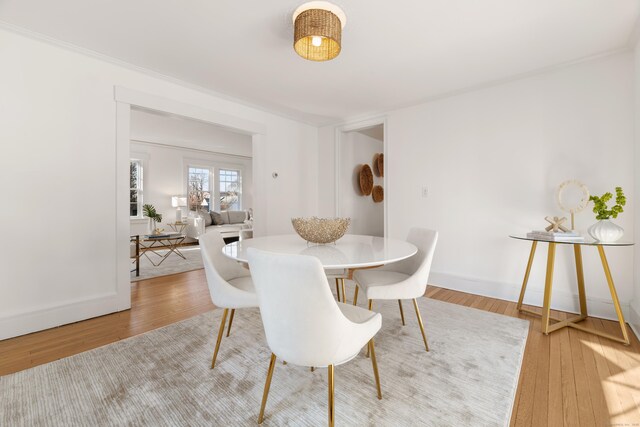 dining space with wood-type flooring and ornamental molding