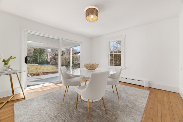 dining room with a baseboard heating unit, crown molding, and light hardwood / wood-style floors