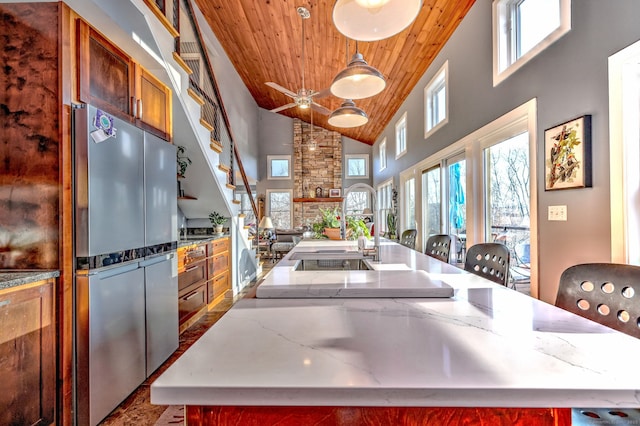 kitchen with hanging light fixtures, a kitchen island with sink, and wooden ceiling