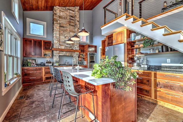 kitchen featuring high vaulted ceiling, pendant lighting, a center island with sink, and stainless steel appliances