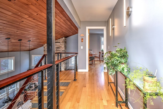 corridor with light hardwood / wood-style floors, vaulted ceiling, and wood ceiling