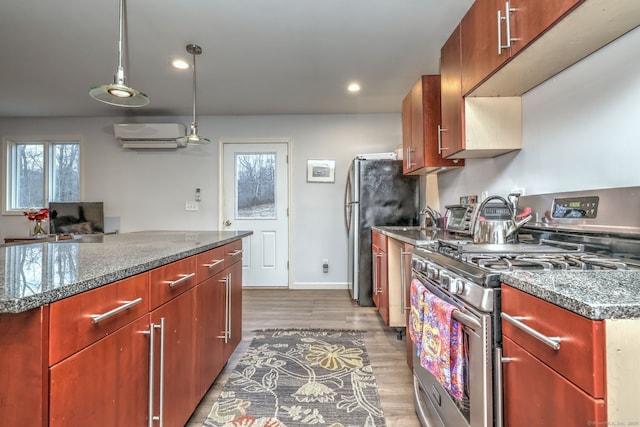 kitchen featuring hardwood / wood-style floors, a kitchen island, stainless steel appliances, hanging light fixtures, and a wall mounted air conditioner