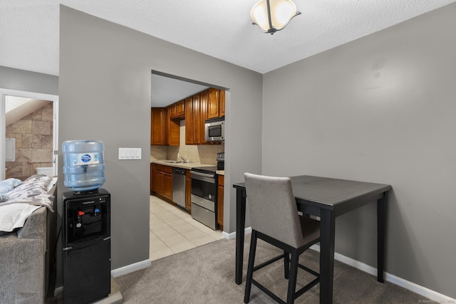 kitchen with light tile patterned flooring, sink, decorative backsplash, stainless steel appliances, and a textured ceiling