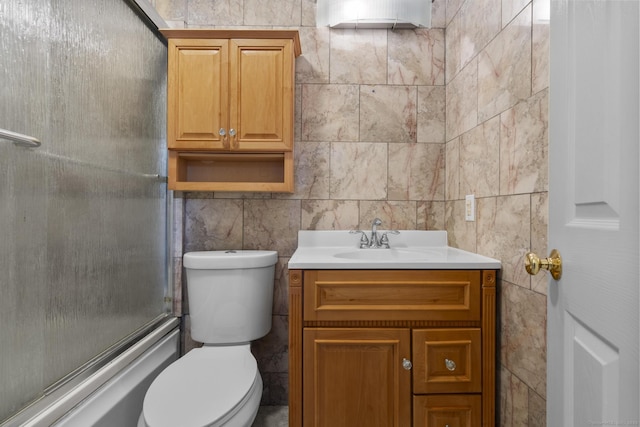 full bathroom featuring vanity, tile walls, enclosed tub / shower combo, and toilet