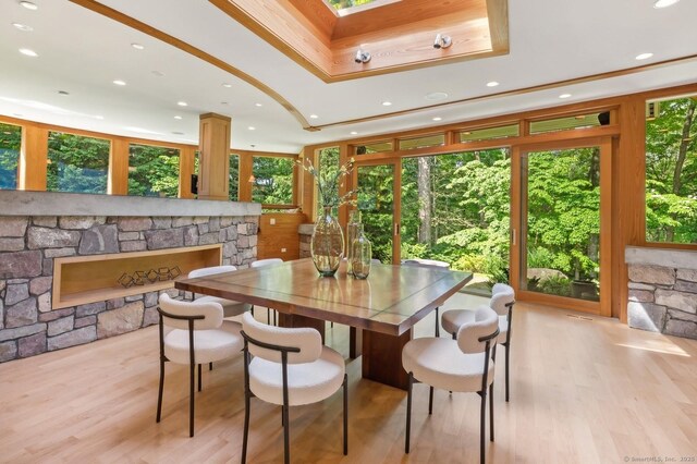 dining space with a tray ceiling, a fireplace, and light wood-type flooring