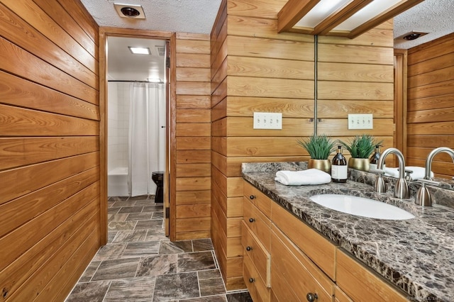 bathroom featuring vanity, wooden walls, and a textured ceiling