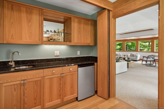 kitchen with sink, light carpet, refrigerator, and dark stone counters