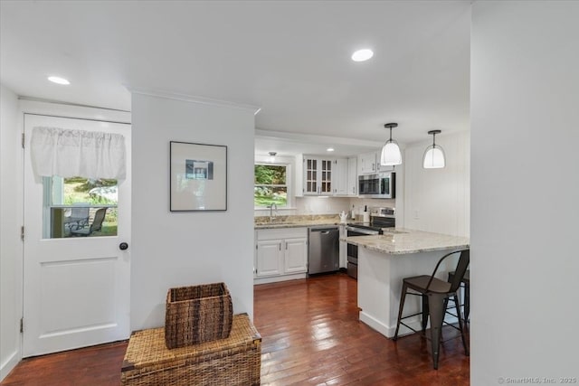 kitchen featuring dark wood finished floors, appliances with stainless steel finishes, glass insert cabinets, a peninsula, and white cabinetry