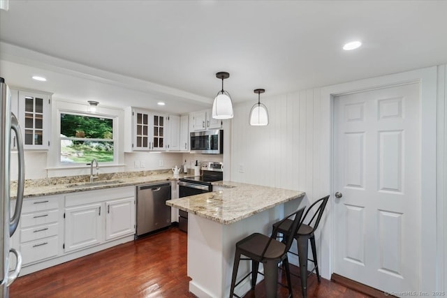 kitchen featuring dark wood-style floors, light stone countertops, stainless steel appliances, white cabinetry, and a sink