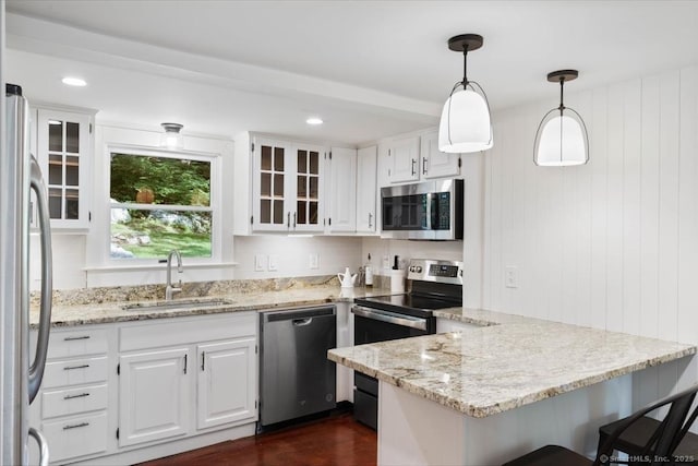 kitchen featuring a peninsula, appliances with stainless steel finishes, a sink, and white cabinetry