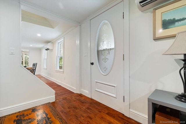 foyer entrance featuring a wall mounted air conditioner, wood finished floors, and baseboards