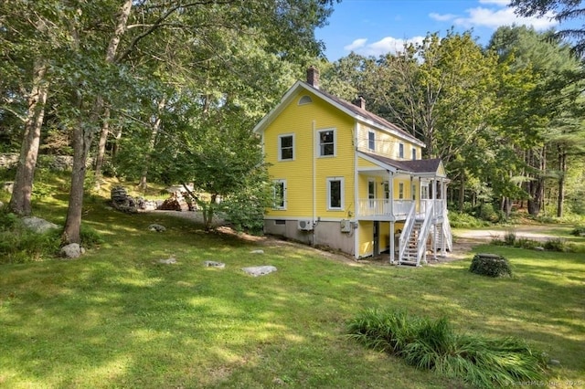 back of house with stairs, a chimney, and a lawn