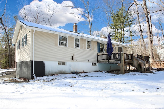 snow covered house featuring a wooden deck