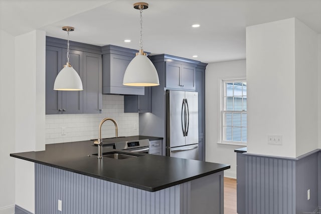 kitchen featuring tasteful backsplash, appliances with stainless steel finishes, decorative light fixtures, and kitchen peninsula