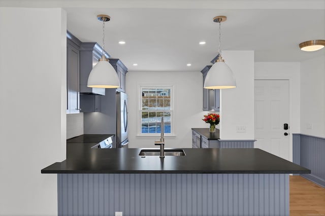 kitchen with tasteful backsplash, hanging light fixtures, kitchen peninsula, and stainless steel refrigerator