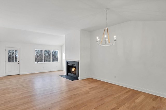 unfurnished living room with a chandelier, vaulted ceiling, and light wood-type flooring