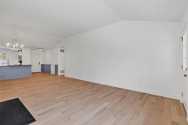 unfurnished living room with lofted ceiling, a chandelier, and light hardwood / wood-style flooring