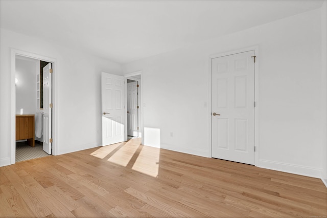 unfurnished bedroom featuring connected bathroom and light hardwood / wood-style floors