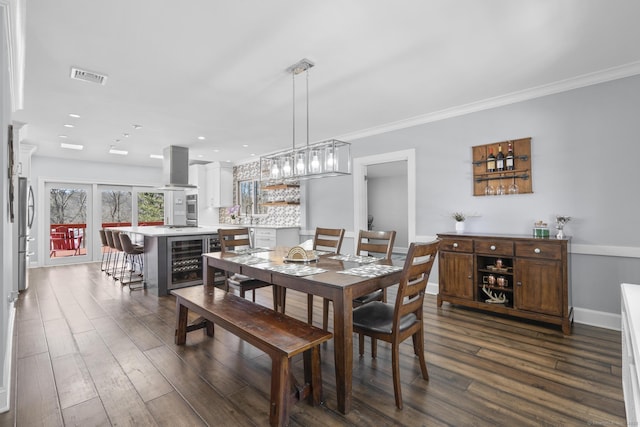 dining space featuring beverage cooler, crown molding, visible vents, and dark wood-type flooring