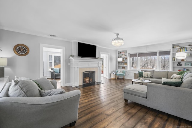 living area featuring dark wood-style floors, ornamental molding, a warm lit fireplace, and visible vents