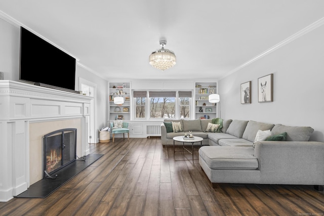 living area with a warm lit fireplace, dark wood-style flooring, built in features, ornamental molding, and radiator