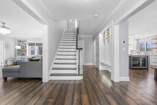 staircase with wine cooler, crown molding, and wood finished floors