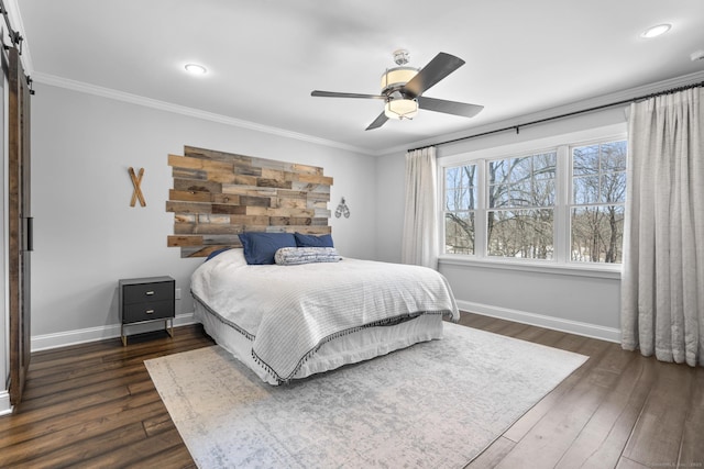 bedroom featuring ornamental molding, a barn door, dark wood-style floors, and baseboards