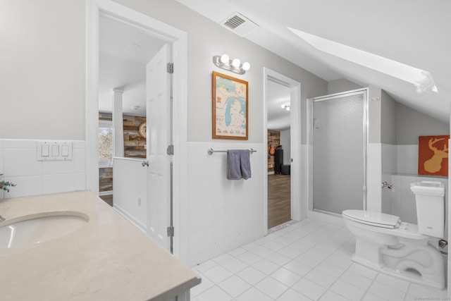 full bathroom featuring tile walls, lofted ceiling with skylight, a shower stall, vanity, and tile patterned flooring