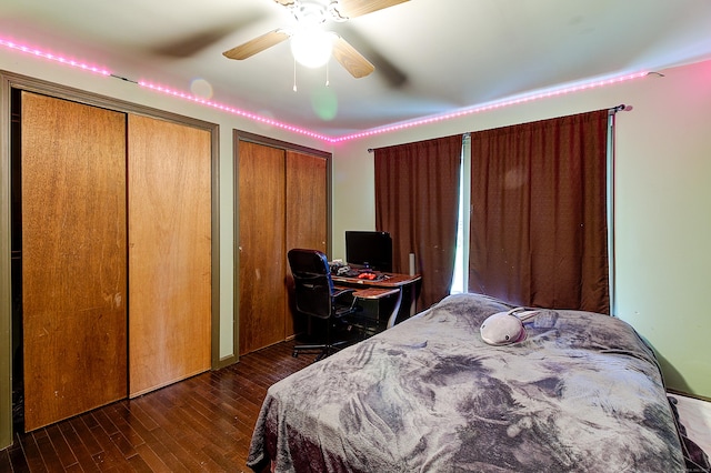 bedroom featuring multiple closets, ceiling fan, and dark hardwood / wood-style flooring