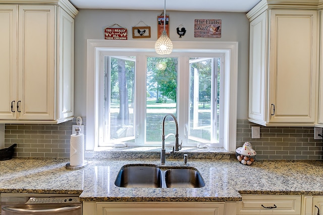 kitchen with sink, cream cabinetry, tasteful backsplash, and hanging light fixtures