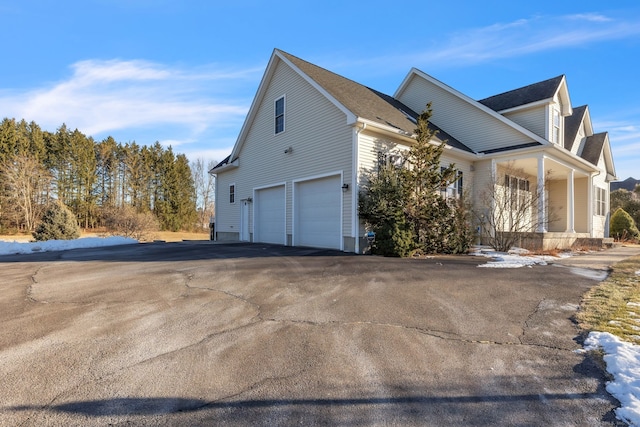 view of side of home featuring a garage and covered porch