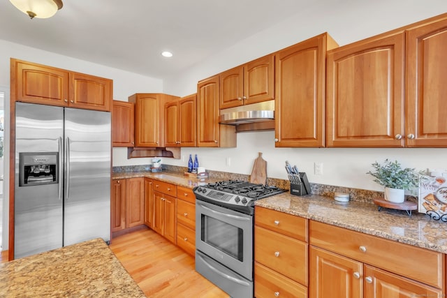 kitchen featuring light stone countertops, stainless steel appliances, and light wood-type flooring