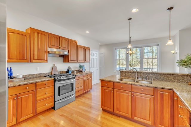 kitchen featuring pendant lighting, sink, light stone counters, gas stove, and light wood-type flooring