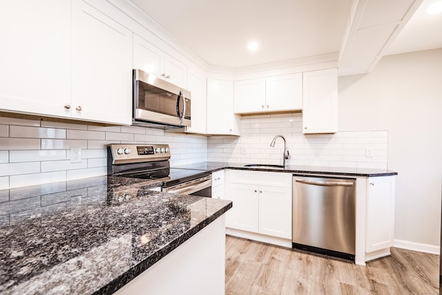 kitchen with white cabinetry, sink, light wood-type flooring, dark stone countertops, and stainless steel appliances