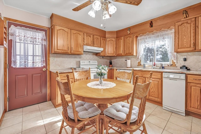 kitchen with light tile patterned flooring, sink, backsplash, light stone counters, and white appliances