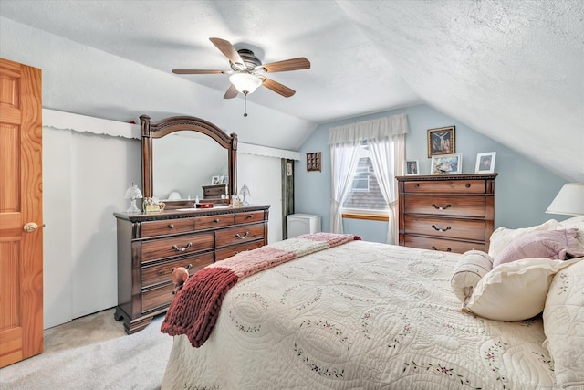 bedroom featuring ceiling fan, vaulted ceiling, light colored carpet, and a textured ceiling