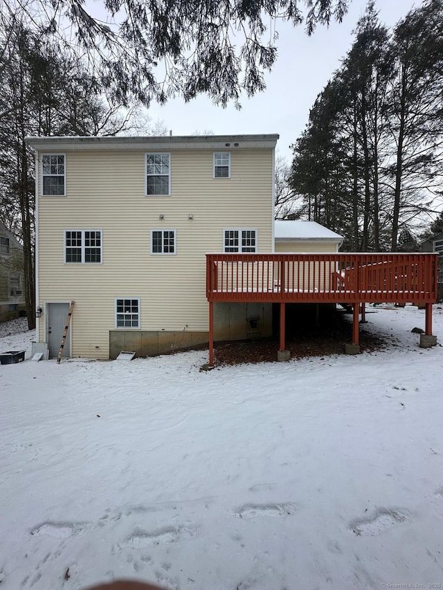 snow covered rear of property featuring a deck