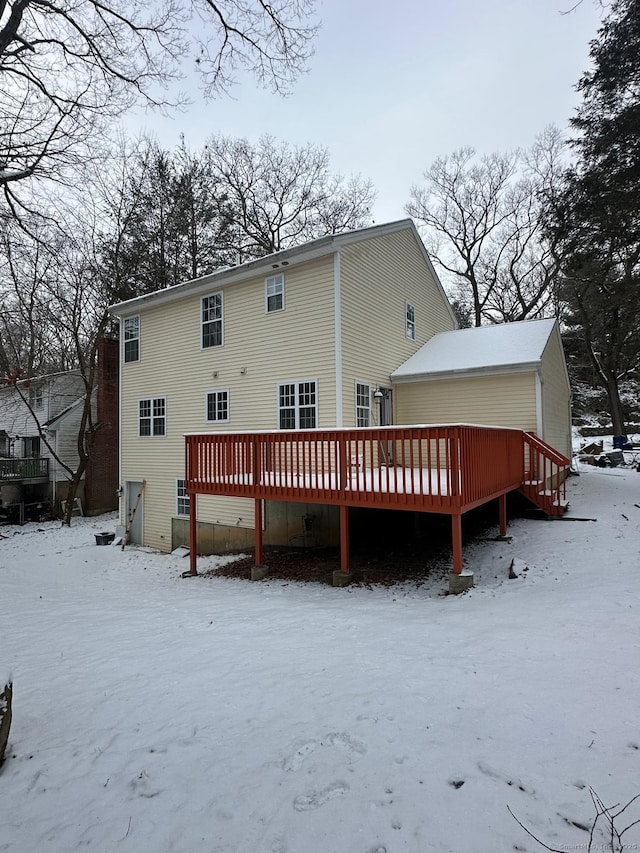 snow covered rear of property with a wooden deck