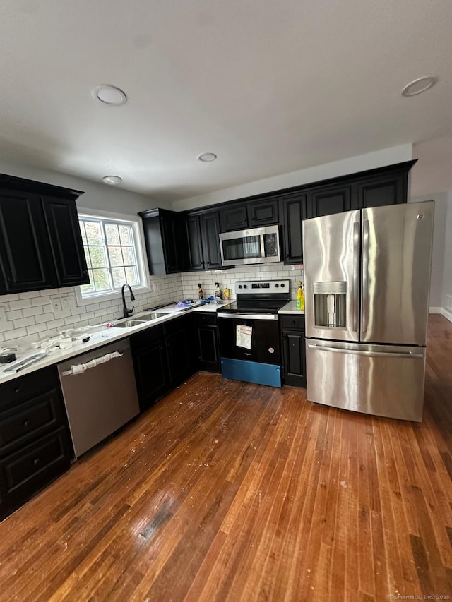 kitchen with dark wood-type flooring, sink, backsplash, and stainless steel appliances