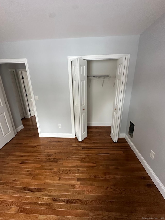 unfurnished bedroom with a closet and dark wood-type flooring