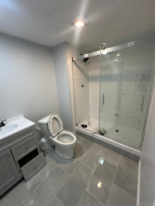 bathroom with a shower with shower door, toilet, and vanity