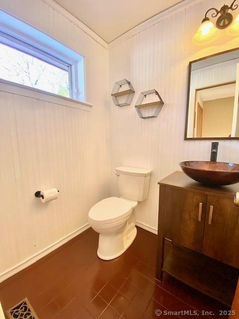 bathroom with toilet, vanity, and ornamental molding